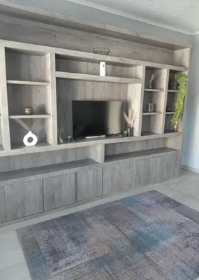 a living room with a large entertainment center with a television at Rihla Residences - Hanbury Road in Cape Town
