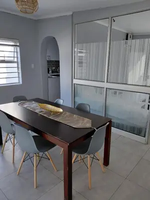 a dining room with a wooden table and chairs at Rihla Residences - Hanbury Road in Cape Town
