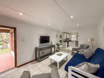 a living room with a blue couch and a tv at Gulls Nest in Hermanus