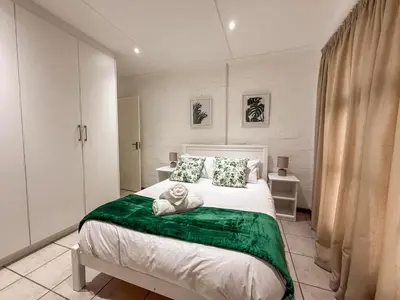 a bedroom with a large bed with a green blanket at Gulls Nest in Hermanus