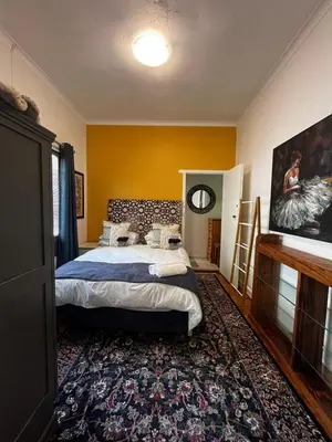 a bedroom with a large bed and a rug at Central Eclectic Studio by ARPA Hospitalities in Stellenbosch