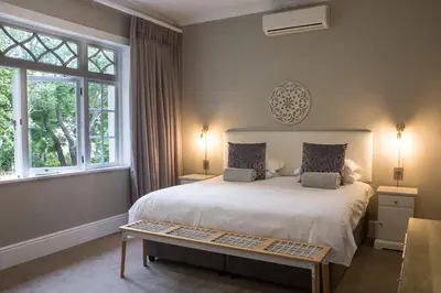 a bedroom with a large white bed and windows at Summerwood Guest House in Stellenbosch