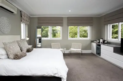 a bedroom with a large white bed and windows at Summerwood Guest House in Stellenbosch