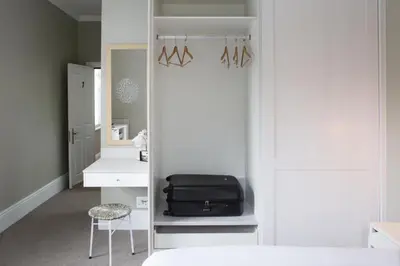 a room with a bedroom with a bed and a suitcase at Summerwood Guest House in Stellenbosch
