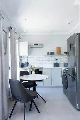 a kitchen with a table and chairs and a refrigerator at CAG The Alxndr Stellenbosch in Stellenbosch