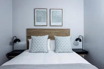 a bedroom with a white bed with two lamps at CAG The Alxndr Stellenbosch in Stellenbosch