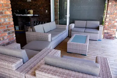 a group of wicker chairs and tables on a patio at Garden Pool Manor House in Kuilsrivier