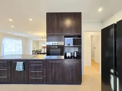 a large kitchen with wooden cabinets and appliances at 12 Sleeper Luxury Villa Chaffinch in Cape Town