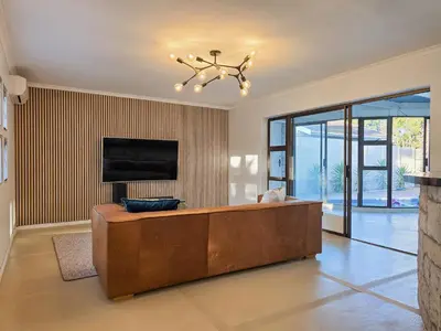 a large living room with a couch and a tv at 12 Sleeper Luxury Villa Chaffinch in Cape Town