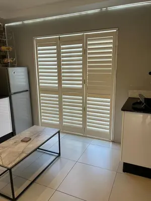 a kitchen with a table and a window with shutters at Home Away From Home 6 minutes away from beach in Cape Town