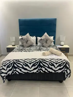 a bed with a blue headboard and pillows on it at Home Away From Home 6 minutes away from beach in Cape Town