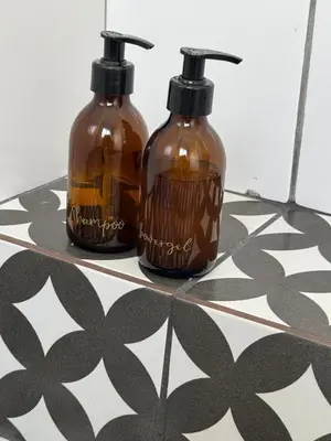 two bottles sitting on top of a tile floor at De Eike in Stellenbosch