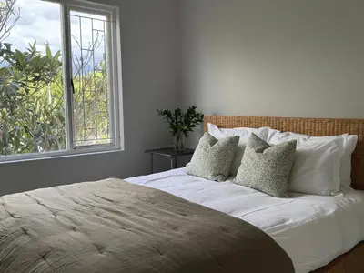 a bedroom with a bed with pillows and a window at De Eike in Stellenbosch