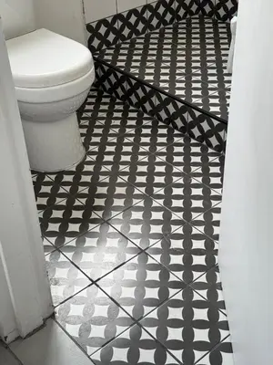a bathroom with a toilet and a black and white tile floor at De Eike in Stellenbosch