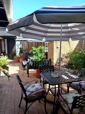 a table and chairs under an umbrella on a patio at Le Bay Lodge in Gordonʼs Bay