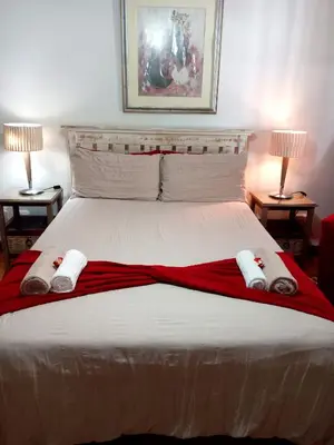 a bedroom with a large bed with two lamps at Le Bay Lodge in Gordonʼs Bay