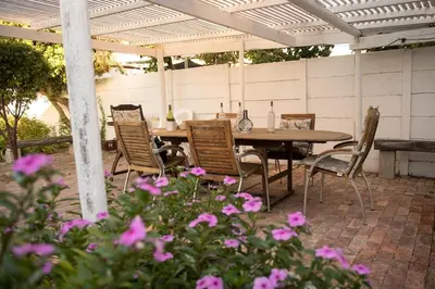 a patio with a table and chairs and flowers at CalTye On Sea in Hermanus