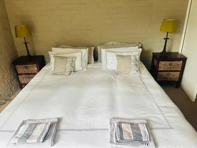 a large bed with white sheets and pillows at Fynbos Mountain View in Kleinmond