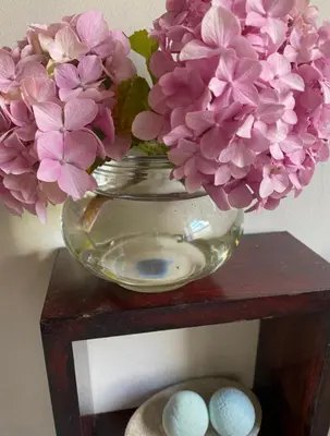 a glass bowl with pink flowers in it on a shelf at Fynbos Mountain View in Kleinmond