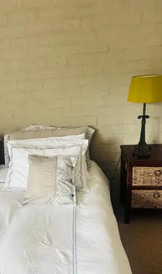 a bed with white pillows and a lamp on a table at Fynbos Mountain View in Kleinmond