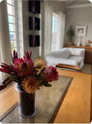 a vase of flowers on a table in a living room at Fynbos Mountain View in Kleinmond