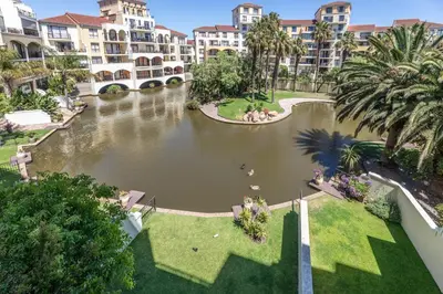 an apartment complex with a pond in the middle at Portifino on lake 221 The Island Club in Cape Town