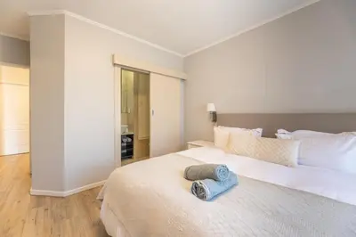 a bedroom with a large white bed with two towels on it at Portifino on lake 221 The Island Club in Cape Town