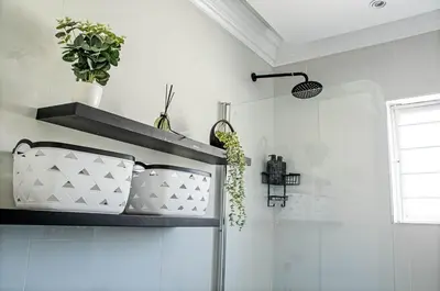 a bathroom with white walls and a shelf with plants at Sukoluhle Guest House in Cape Town