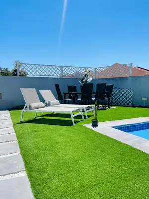 a white bench sitting on the grass next to a pool at Sukoluhle Guest House in Cape Town