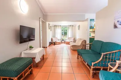 a living room with a couch and chairs and a tv at Die Steenbras in Fisherhaven