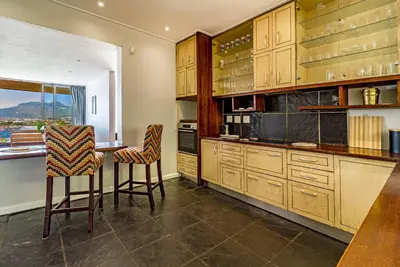 a kitchen with wooden cabinets and a table and chairs at 5 Suikerbossie in Gordonʼs Bay