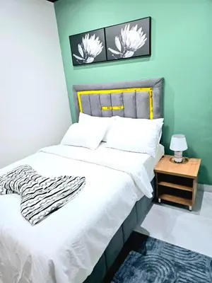 a bedroom with a bed with white sheets and a side table at Evernice Guest House in Cape Town
