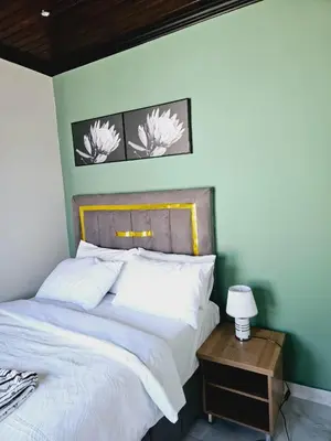 a bedroom with a white bed with a wooden headboard at Evernice Guest House in Cape Town