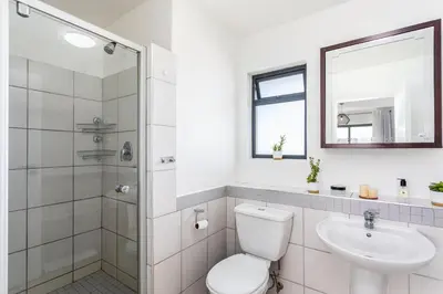 a white bathroom with a toilet and a sink at Knightsbridge 702W by CTHA in Cape Town