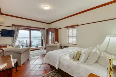 a bedroom with a bed and a living room at Berg en Zee Guesthouse in Gordonʼs Bay