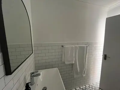 a bathroom with a sink and a mirror and towels at The Sultan Cottage in Stellenbosch