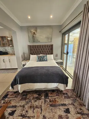 a bedroom with a large bed and a large window at Induli on Sage in Plattekloof