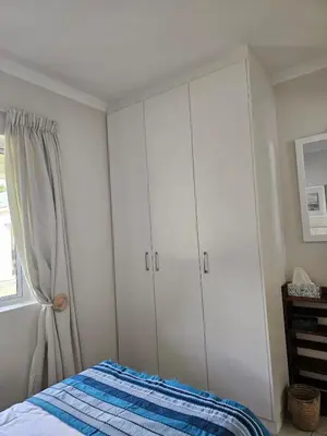 a bedroom with white cabinets and a bed at Torbrae Cottage in Hermanus