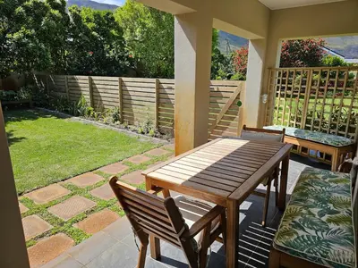 a porch with a wooden table and chairs on a patio at Torbrae Cottage in Hermanus