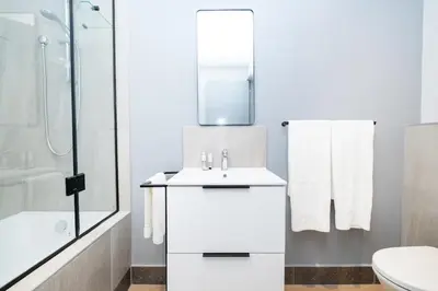 a white bathroom with a sink and a shower at 721 Riverlands - Lux 2 Bedroom Apartment in Cape Town