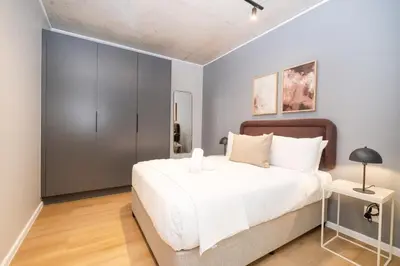 a bedroom with a white bed and a gray cabinet at 721 Riverlands - Lux 2 Bedroom Apartment in Cape Town