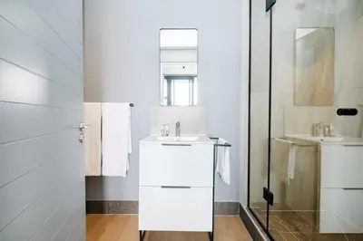 a white bathroom with a sink and a shower at 721 Riverlands - Lux 2 Bedroom Apartment in Cape Town