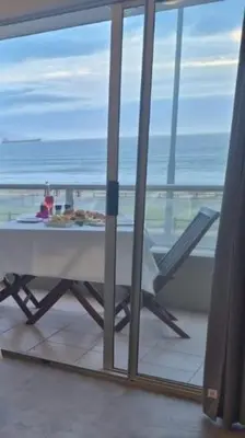a table on a balcony with a view of the ocean at Seaspray Apartment Blauberg in Cape Town