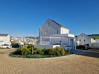 a white house with a car parked in a driveway at Casa Voliere in Stellenbosch