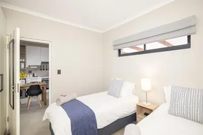 a small bedroom with two beds and a kitchen at Durbanville Daydream in Durbanville