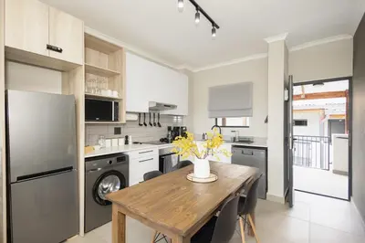 a kitchen with a wooden table and a refrigerator at Durbanville Daydream in Durbanville