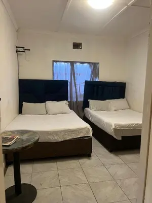 a bedroom with two beds and a table and a window at Heritage lodge in Cape Town