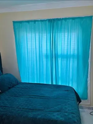 a bedroom with a blue bed with a blue curtain at Vasco Geusthouse in Goodwood