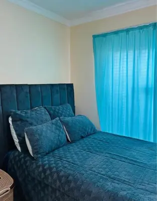 a bedroom with a blue bed with a blue curtain at Vasco Geusthouse in Goodwood