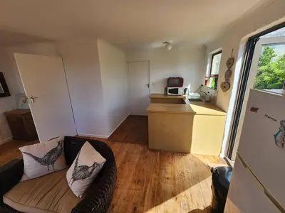 a living room with a couch and a kitchen at The Sandpiper - The Alikreukel , Pringle Bay in Pringle Bay